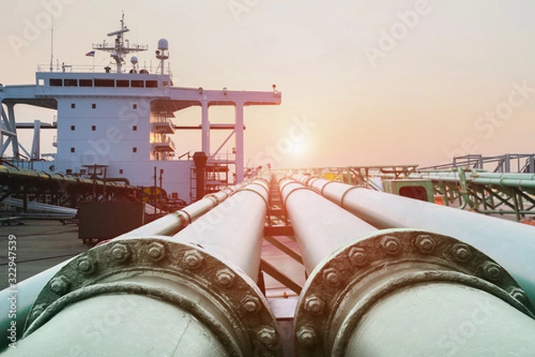 Obraz Steel long pipe connect in crude oil factory, On deck of chemical tanker ship with pipe line connection while the ship on acccomomodation deck background and sunset