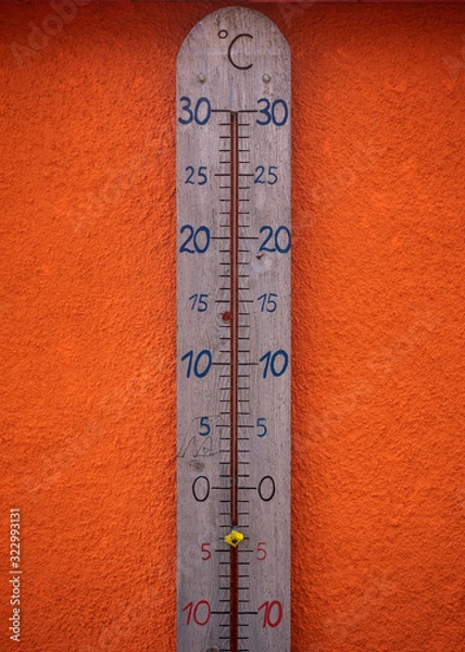Obraz A huge wooden thermomater showing minus degrees, in front of a bright orange wall.