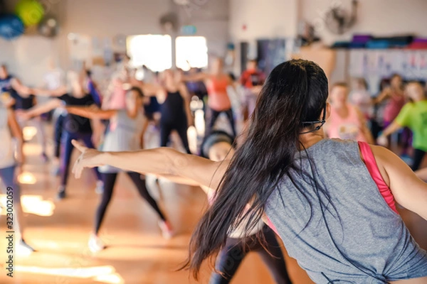 Obraz Blurred group of women in dancing aerobics class. Rear View of the trainer. Activity and healthy life style.