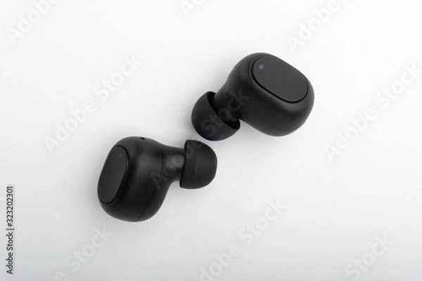 Obraz Wireless earbuds or earphones on white background. Copy space and technology concept