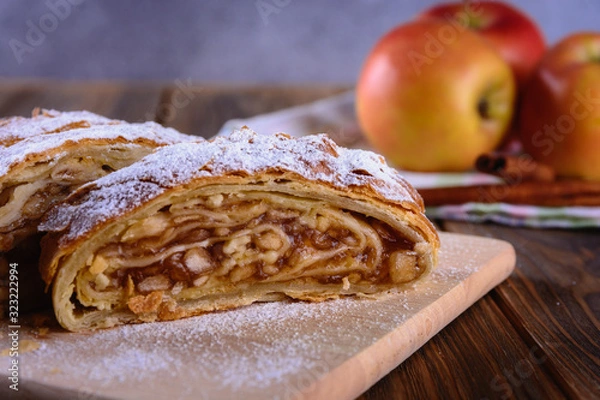 Fototapeta Delicious strudel stuffed with apples and cinnamon and red apples on background