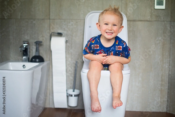 Obraz Happy little baby boy sitting on toilet and training to urinate and defecate into