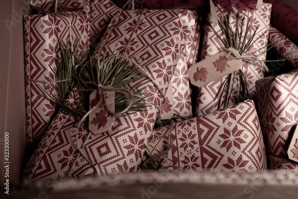 Fototapeta Many secret christmas presents piled up with creative handmade  rustic diy gift wrapped in retro wrapping paper with natural vintage twine and spruce twigs as decor, hidden away until Xmas Eve