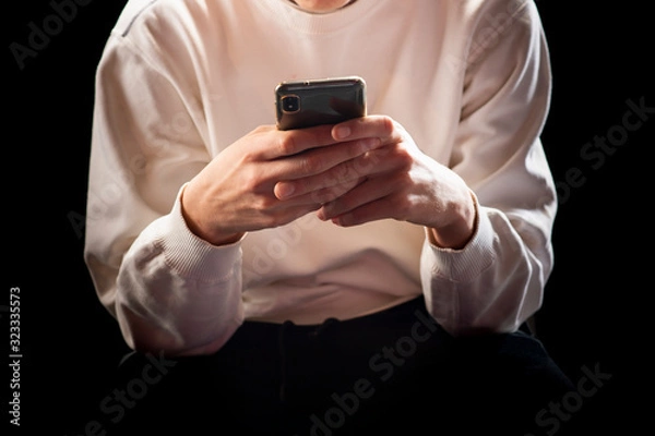 Fototapeta Young man in a sports suit with a smartphone