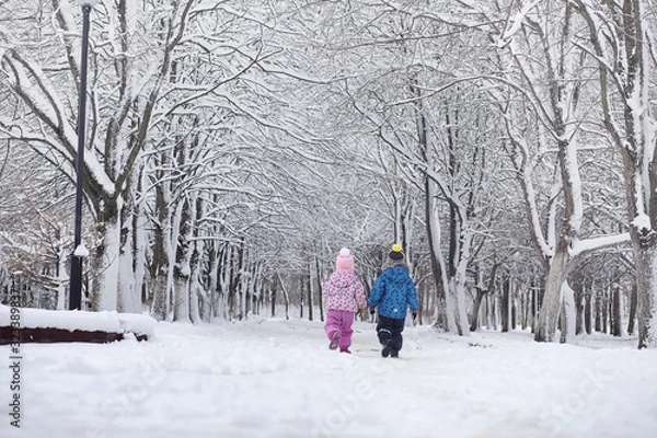Fototapeta Snow-covered winter park and benches. Park and pier for feeding ducks and pigeons.Family on a walk in the snow covered the park.