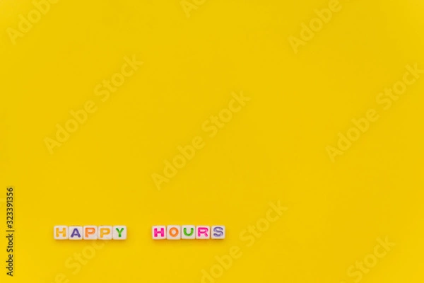 Fototapeta Happy Hours written by white cube with multocolor letters on yellow background