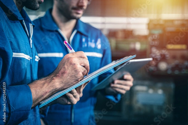 Obraz Inspector engineers writing on a clipboard with a pen. Routine maintenance inspection checklist.
