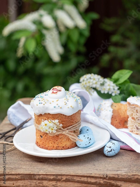 Fototapeta Easter composition with Easter cake, Kulich on the background of flowering branches of bird cherry in the garden. delicious easter dessert. vertical image
