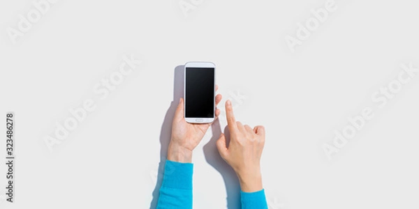 Fototapeta Person using a white smartphone - overhead view