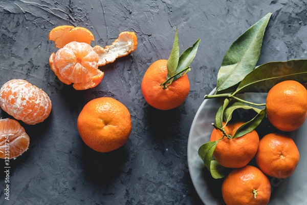 Fototapeta Juicy ripe tangerines with leaves on wooden table
