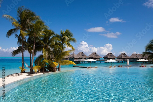 Fototapeta French Polynesia. Over water bungalows, sandy beach with palm trees and pool, Bora Bora..
