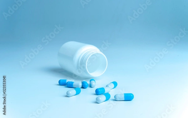 Fototapeta Bottle and scattered pills on color background, top view