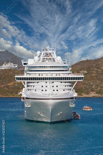 Fototapeta A white cruise ship anchored in a bay with people loading into lifeboats