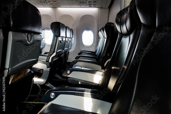 Fototapeta Empty passenger seats in airplane with light shining through the window.