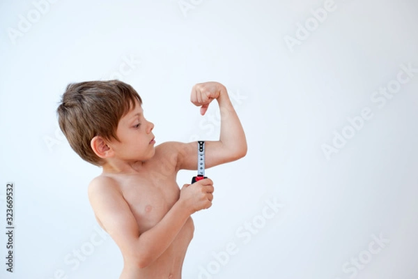 Obraz funny healthy little caucasian boy measuring his strong muscle using tape on white backgroun with copy space