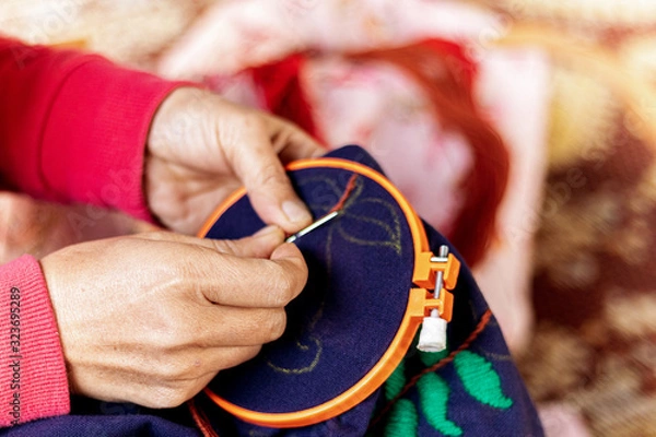 Fototapeta Asian woman's hand is embroidered with tribal native fabric. Sewing pattern. Embroidery in the embroidery frame.