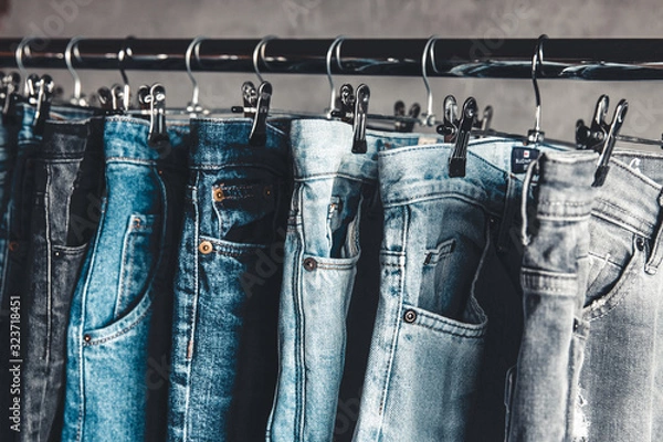 Fototapeta Rack with different jeans on grey background