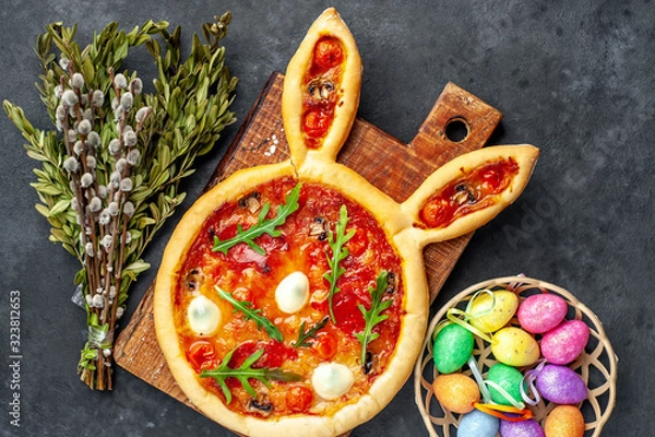 Fototapeta Festive Easter pizza in the form of a rabbit with eggs, colorful  Easter eggs and willow on a stone background. Easter celebration concept.