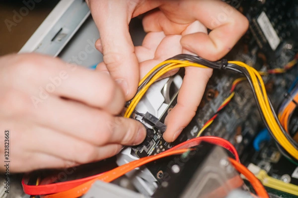 Fototapeta Professional system administrator holds in hands sockets connectors of standard power supply unit. man repairing and assembling computer. concept of repair computer. Selective focus