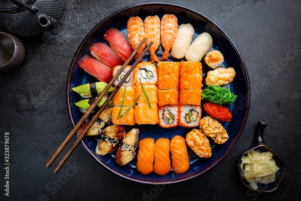 Fototapeta Set of sushi and maki with soy sauce over black background. Top view with copy space