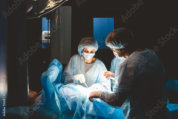 Fototapeta The senior surgeon in the operating room, where the patient is waiting for him, and he begins the operation. Real Modern Hospital with Authentic Equipment.