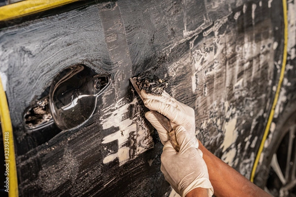 Fototapeta Auto mechanic is using chemical corrosion paint, automobile ,Remover old paint. Manual work with scraper. preparation for painting a car.