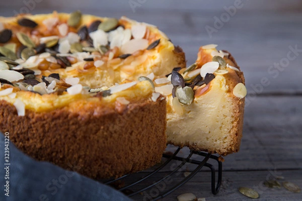 Fototapeta Cheesecake Tart With Pears, Pumpkin Seeds and Almond Petals On Wooden Table with Caramel. Fall Baking Concept.