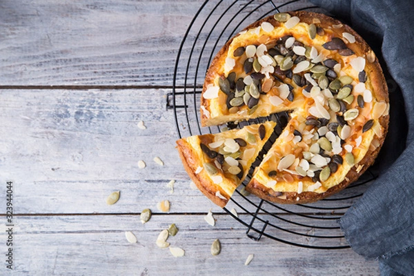 Fototapeta Pears and cheese pie with bowl of caramel, pumpkin seeds and almond petals. Top view. Copy space flat lay