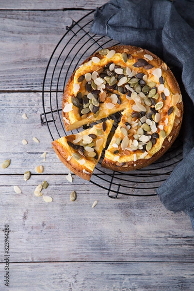 Fototapeta Pears and cheese pie with bowl of caramel, pumpkin seeds and almond petals. Top view. Copy space flat lay