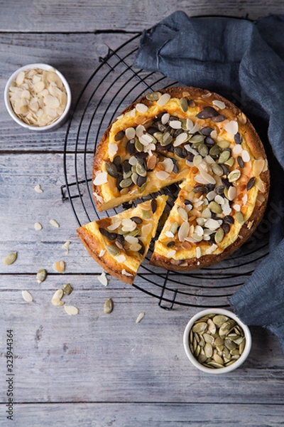 Fototapeta Pears and cheese pie with bowl of caramel, pumpkin seeds and almond petals. Top view. Copy space flat lay