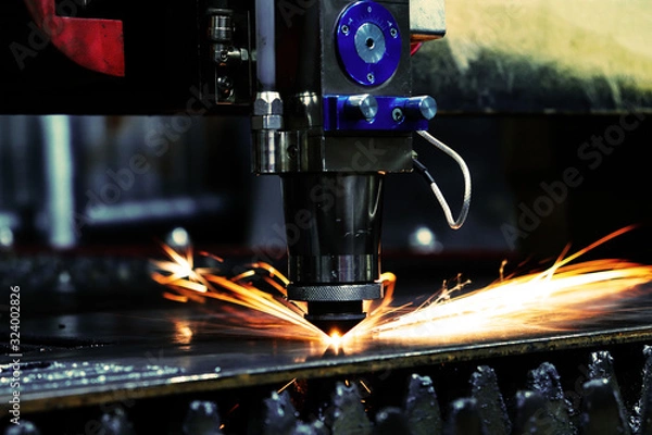 Fototapeta The laser machine cuts a metal sheet and bright sparks fly out of its work. Laser machine at a metalworking factory.