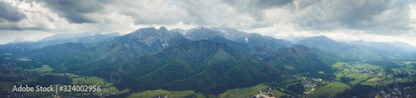 Fototapeta Panoramic drone view of idyllic green town with giant High Tatras mountain range. Zakopane, Poland