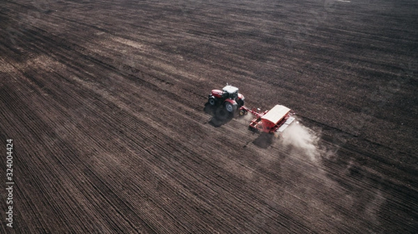 Fototapeta Aerial view of beautiful agriculture landscape and tractor on the field, harvesting the wheat from the soil.