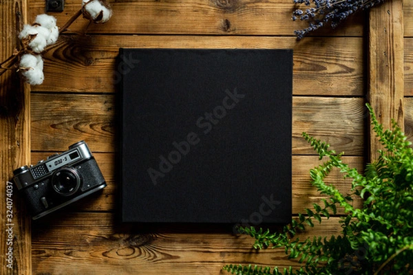 Fototapeta Black book on a wooden table, view from top, old camera FED 5
