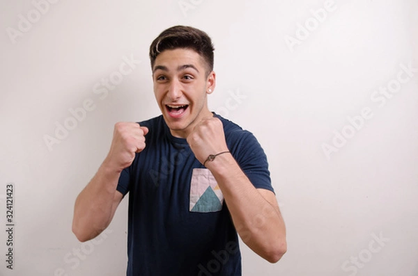 Obraz Happy young man with raised fists showing success