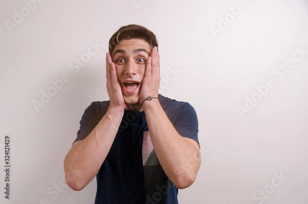 Obraz Surprised young man with hands on face