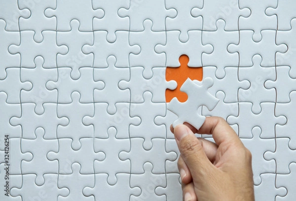 Obraz Pieces of jigsaw puzzle in woman hands,Jigsaw puzzle white color on orange background