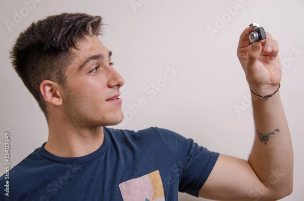 Obraz Young man taking a selfie with a mini camera