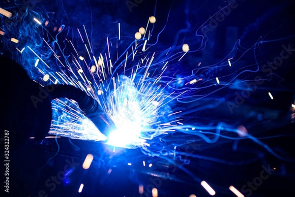 Fototapeta The process of welding metal in the dark with the formation of a large amount of smoke and sparks.