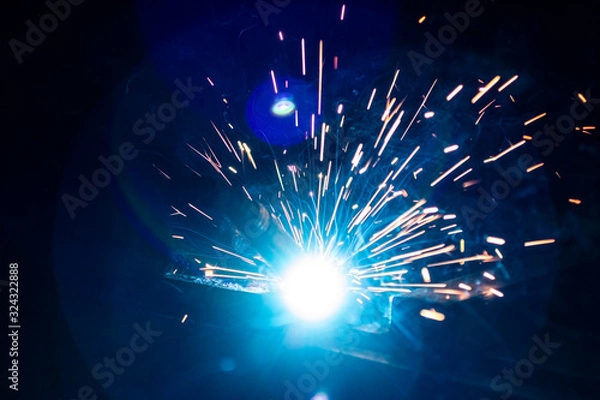 Obraz The process of welding metal in the dark with the formation of a large amount of smoke and sparks.
