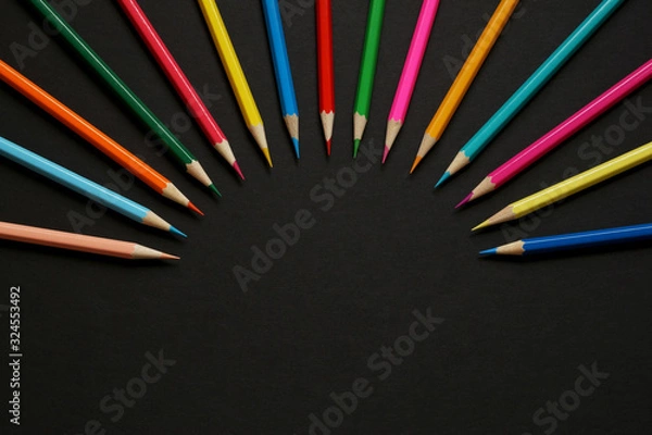 Fototapeta Top view of colored pencils arranged in a semicircle in the form of rays on a dark background 