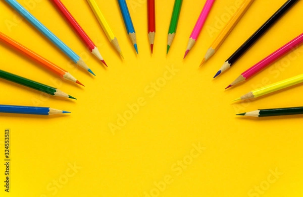 Fototapeta Top view of colored pencils arranged in a semicircle in the form of rays on a yellow background  