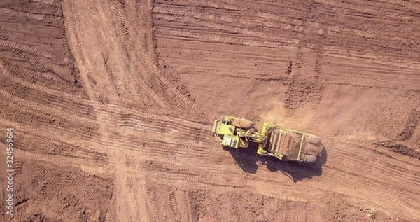 Fototapeta Earthmoving equipment: Bulldozer pushing large amount of fresh soil at large piece of land.