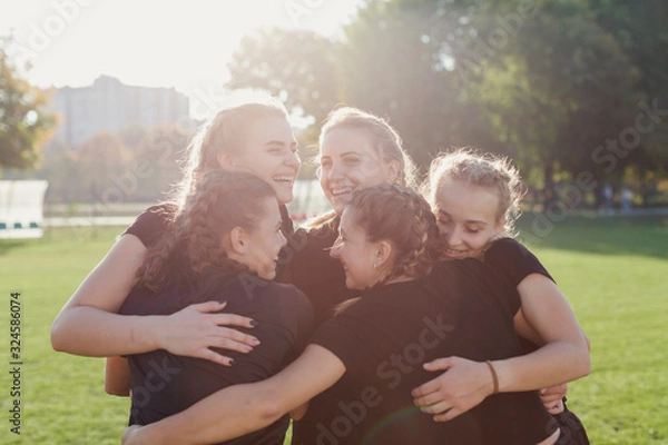 Obraz Sportive women embracing on a football pitch