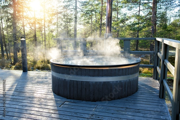 Fototapeta Nowoczesna wanna z hydromasażem na świeżym powietrzu z dużą beczką w środku lasu. Kojąca ciepła woda w wannach z hydromasażem rozluźnia mięśnie i łagodzi napięcia, dzięki czemu Twoje zmartwienia mogą po prostu zniknąć.