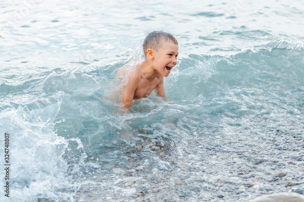 Obraz little girl in a swimsuit splashing her legs in the sea