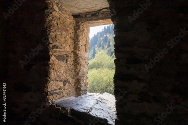 Fototapeta A window  inside a lonely riverbank at the foot of the mountains of the watchtower - Koshki - called the Tower of Love in Svaneti in the mountainous part of Georgia