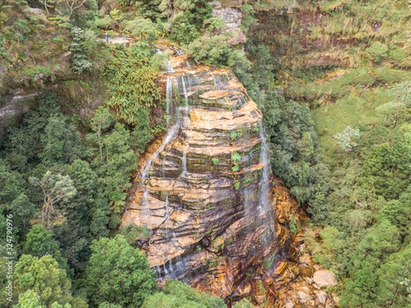 Fototapeta Waterfalls in Blue Mountains Australia. DRONE. Dramatic views of peaks, rock, valley, landscape, green rainforest jungle. Adventure, freedom, fun concepts. Tourist mountain trek. Shot in Sydney, NSW.