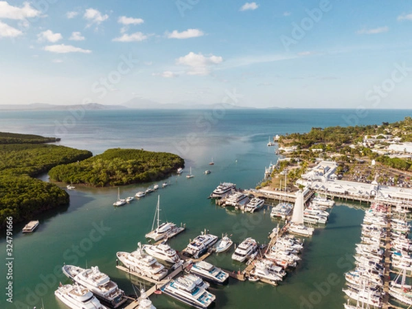 Fototapeta Marina town with waterfront river view of yachts and boats in sea water. Carins Port Douglas aerial view. Dramatic DRONE view from above. Mountain landscape in background. Queenstown, Australia.