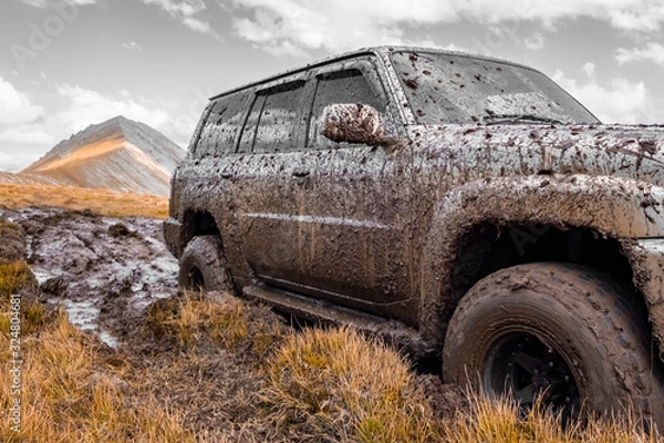 Fototapeta Adventure travel concept background. 4x4 off-road suv car stuck in mud. Adventure travel concept background. Offroad car.